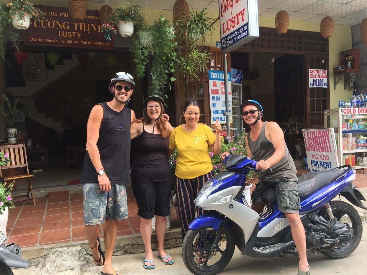 A group of people posing in front of a building with a sign for 'CUONG THINH LUSTY'.