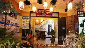 A hotel entrance with a sign for 'CUONG THINH LUSTY' and a staircase leading inside. There are bicycles parked outside and a signboard advertising taxi services. - Homestay Cuong Thinh (Da Nang)