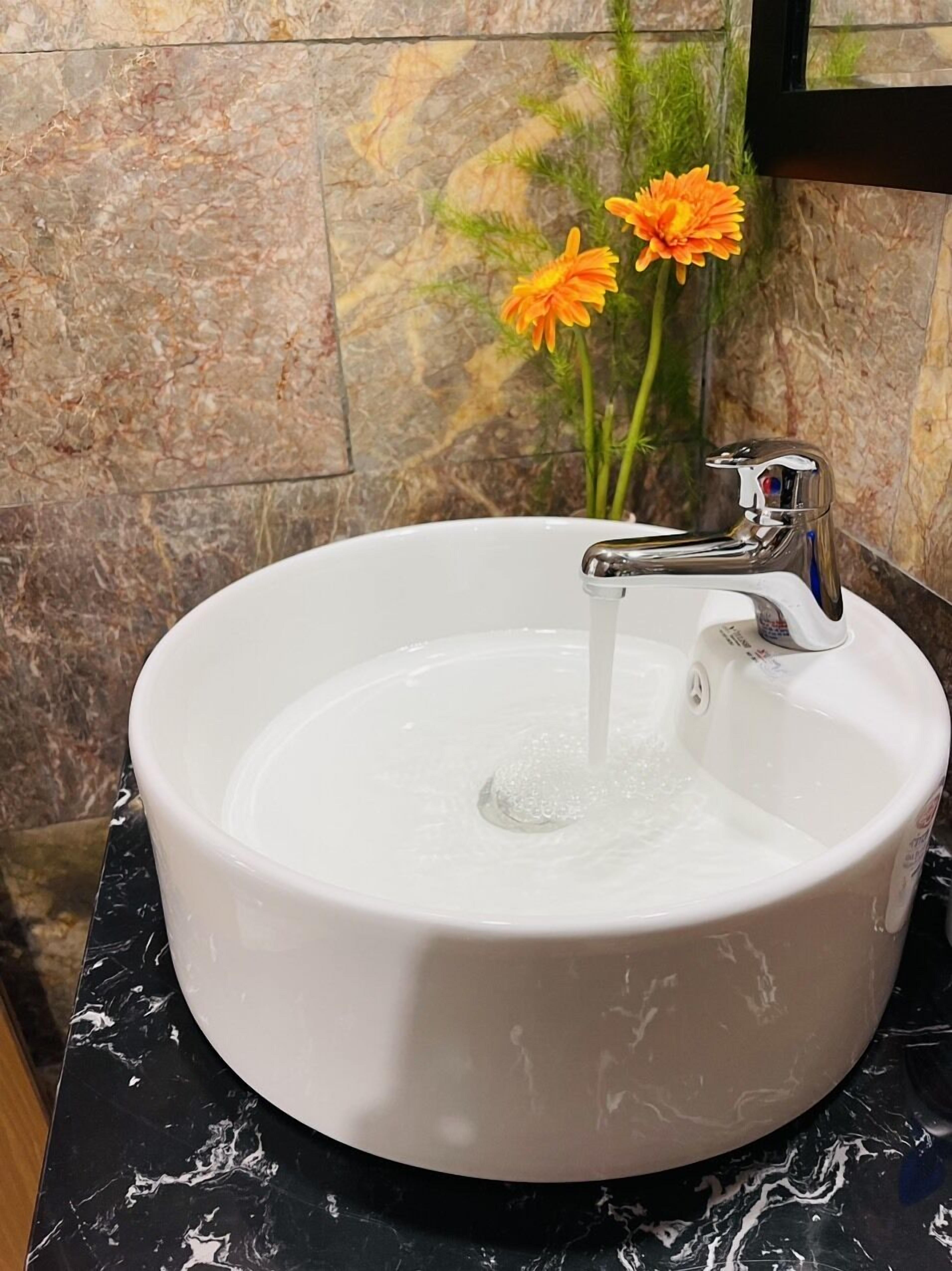 A white ceramic sink with a modern faucet, set against a marble countertop.