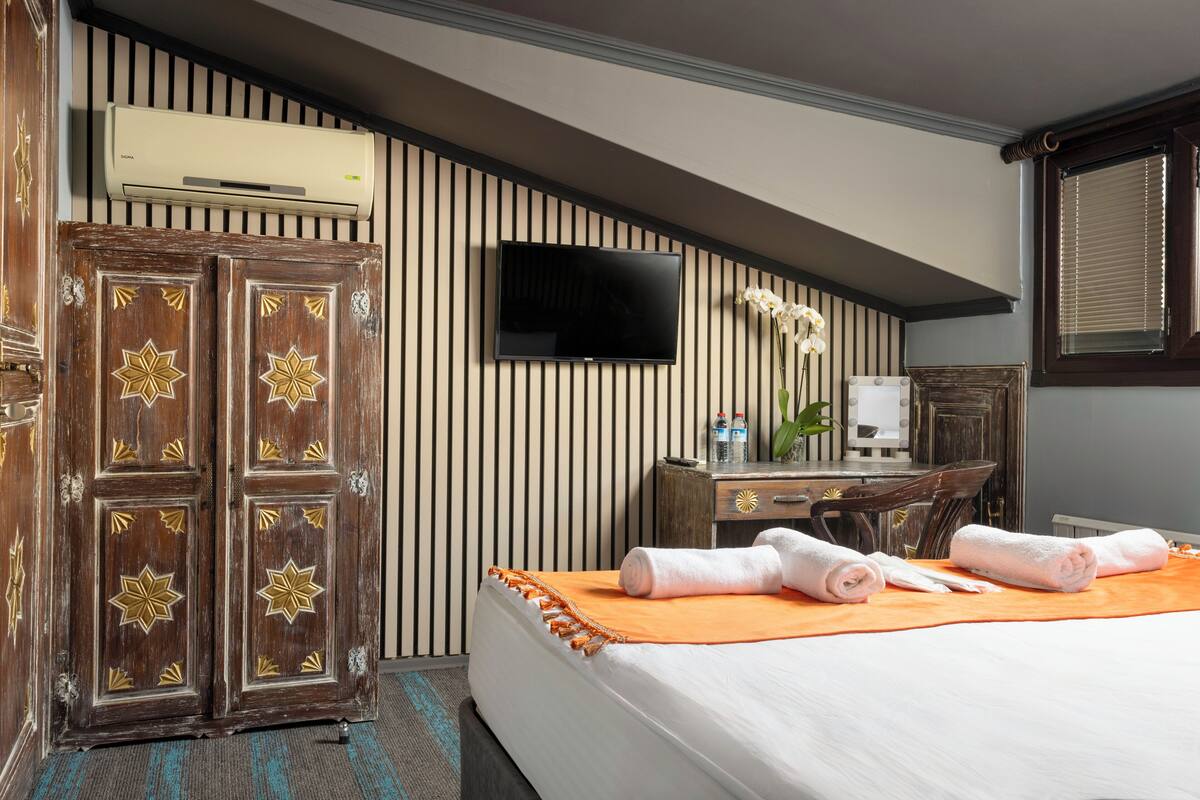 Una habitación de hotel con cama, televisión, escritorio con silla y armario.