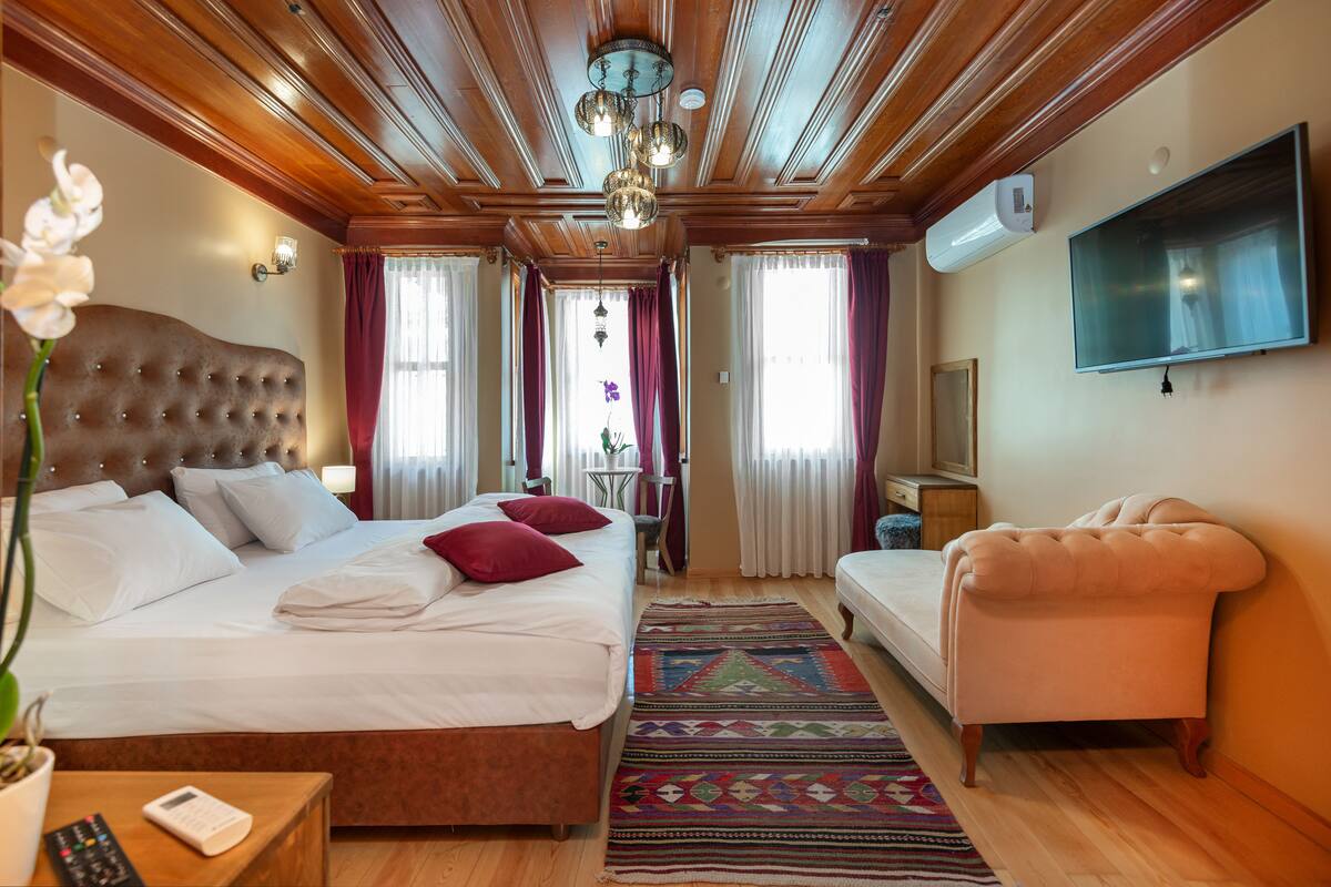Una habitación de hotel con una cama grande, un sofá, un televisor y un techo de madera.