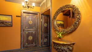 A hallway with ornate wooden doors, a large mirror with a floral frame, and a small table with a potted plant. - Wonder Wood Hotel (Istanbul)