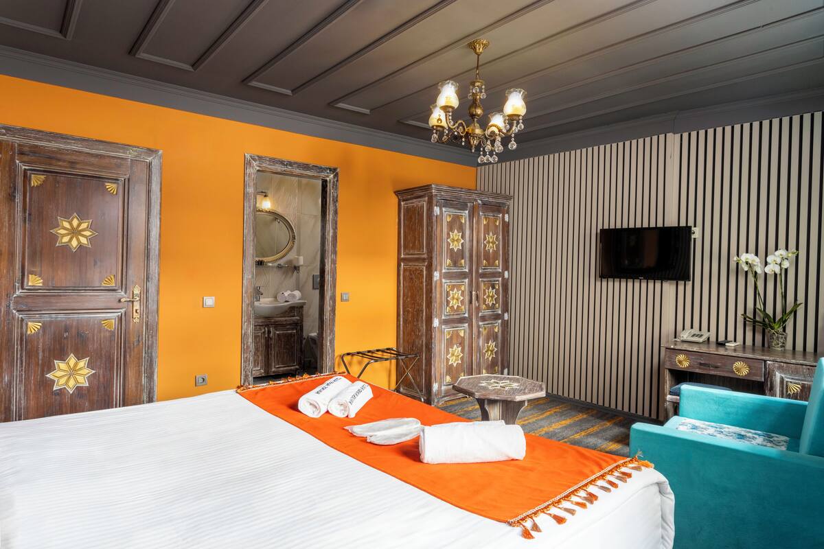 Una habitación de hotel con cama, escritorio, silla, televisor y espejo.