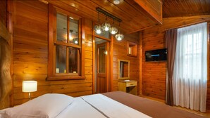 A wooden cabin room with a bed, a nightstand, a mirror, a television, and a window with curtains. - Wonder Wood Hotel (Istanbul)