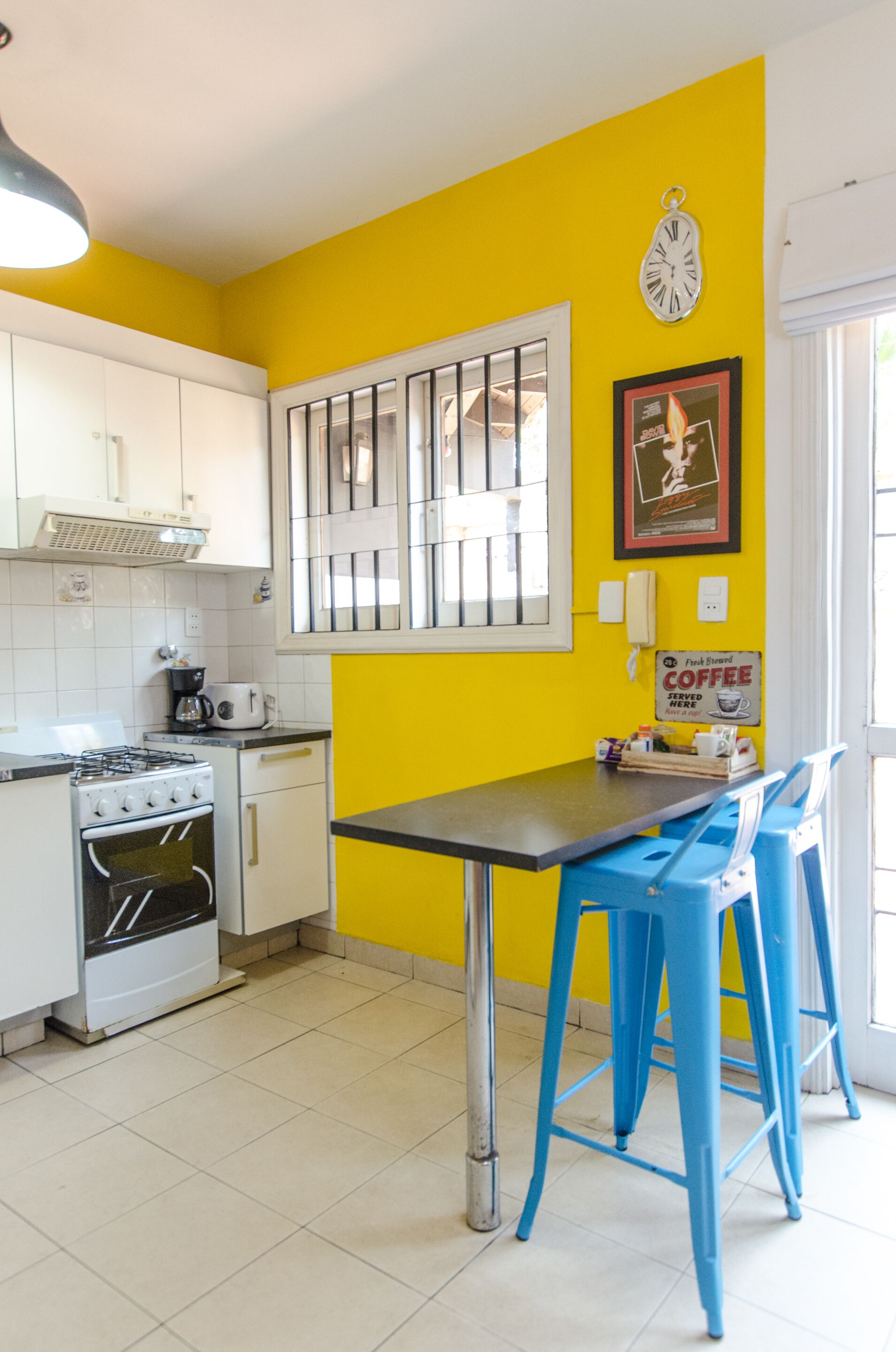 A kitchen with white cabinets, a stove, and a table with blue chairs.