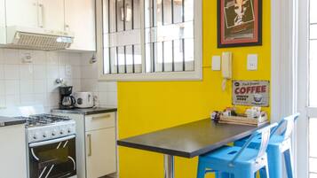 A kitchen with white cabinets, a stove, and a table with blue chairs.
