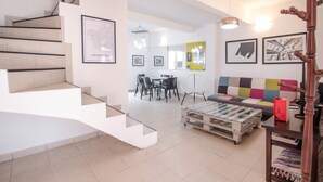 Un intérieur moderne avec un escalier, un coin repas et un canapé coloré.