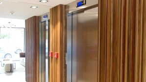 Un couloir au design moderne, avec des murs recouverts de lambris en bois et un ascenseur en acier inoxydable.