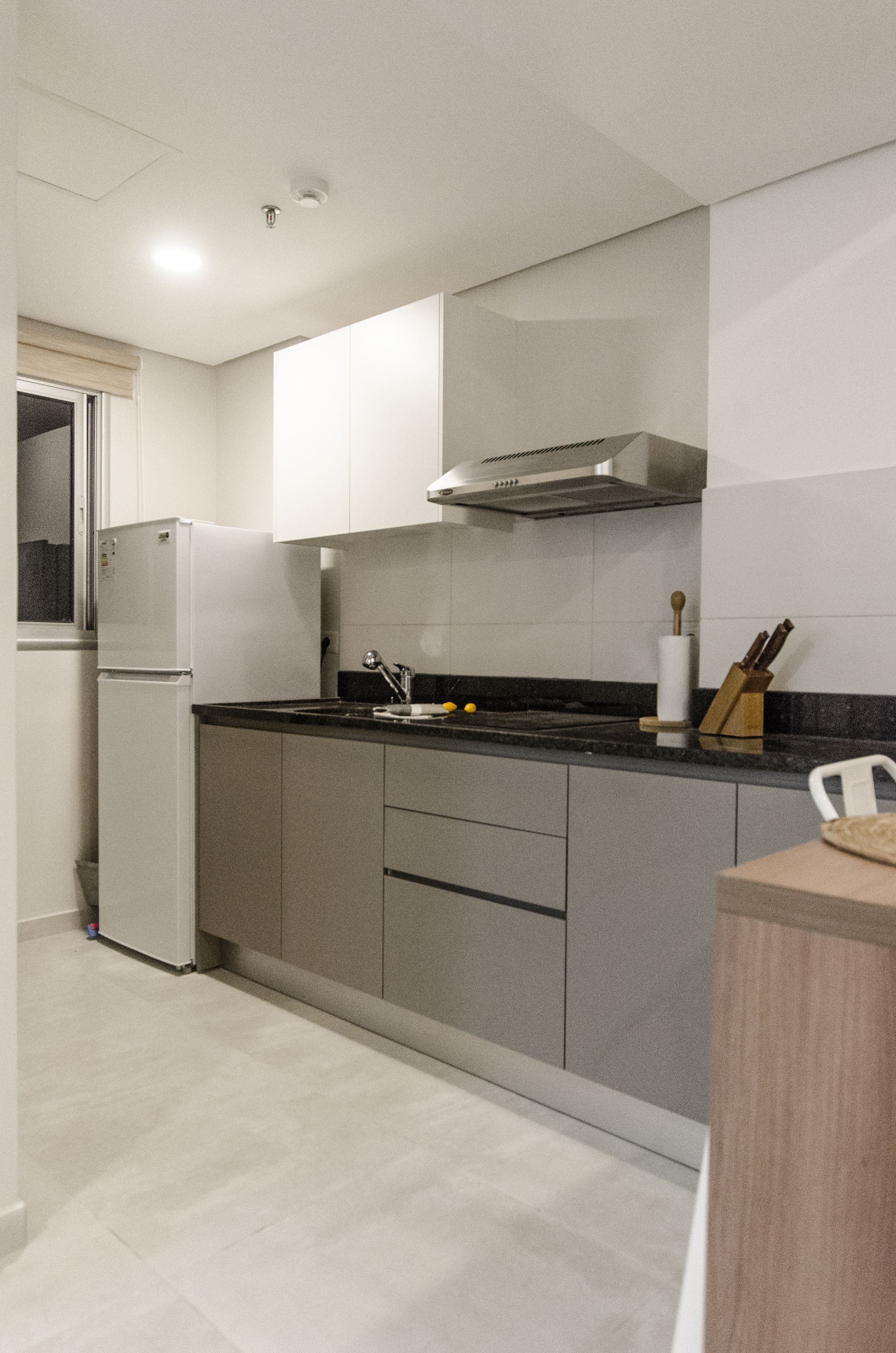 A modern kitchen with white cabinets, a black countertop, and a stainless steel range hood.