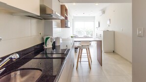 Eine moderne Küche mit Granitabdeckung, Edelstahlgeräten und einem Essbereich in Weiß mit Barhocker.