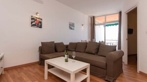 A living room with a brown sofa, a white coffee table, and two wall-mounted picture frames. - Cristianmar 3 - One Bed (Los Cristianos)