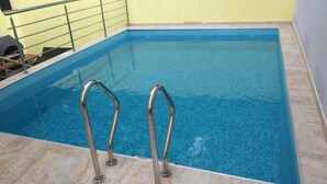 Piscina interior com grades de metal e piso azulejado.