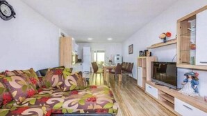 Uma sala de estar moderna com sofá, TV e armários de madeira.