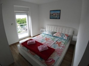 Ein Schlafzimmer mit Bett, Fenster und einem Bild an der Wand.