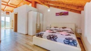 Quarto com teto de madeira, cama com roupa de cama floral, guarda-roupa e banheiro com espelho.