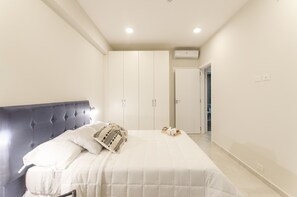 A bedroom with a large bed, a wardrobe, and an air conditioning unit on the wall. - Premium LifeVillamorra 2 Bd Pool & BBQ (Asunción)