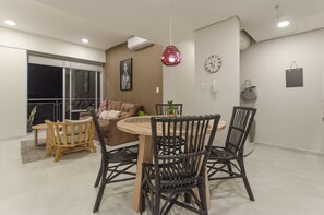 Un espace repas comprenant une table ronde, des chaises noires, un canapé marron et une suspension.