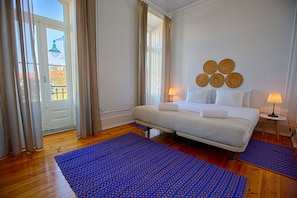 A hotel room with a bed, two bedside lamps, a blue patterned rug, and a view of the outside through a window. - Chalet D Ávila Guest House (Lisbon)