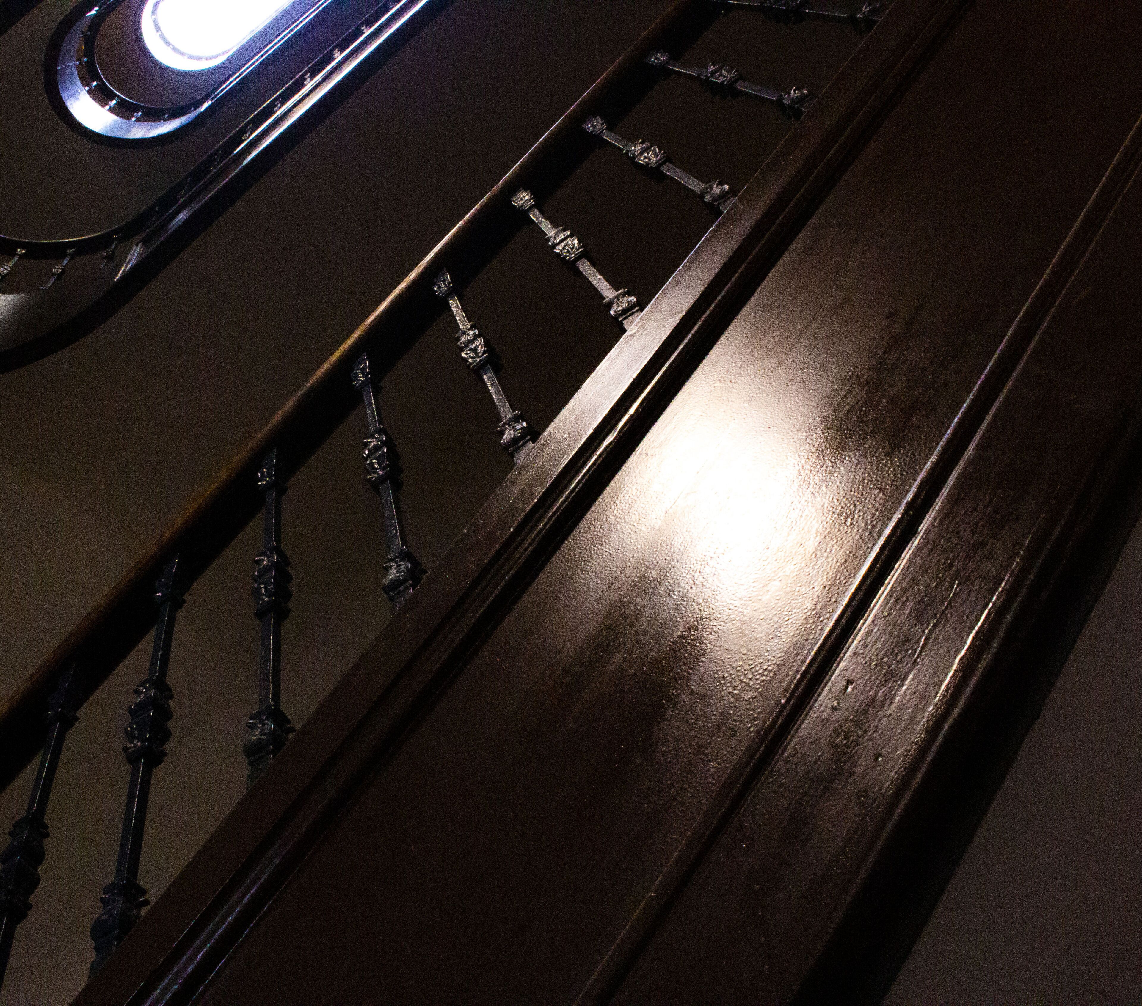 A close-up of a dark wooden surface with metal fixtures, possibly part of a staircase or railings.