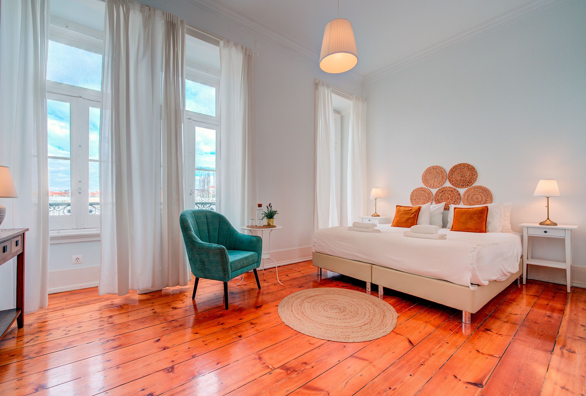 Une chambre à coucher comprenant un lit, une chaise, une table de chevet, une lampe et une vue sur l’extérieur.