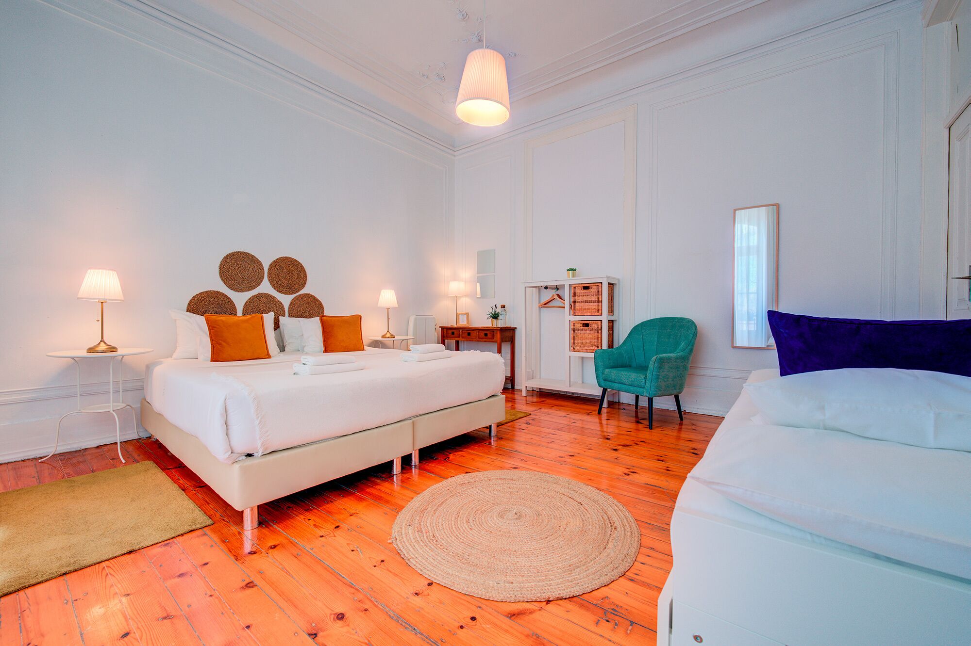 A hotel room with a large bed, two bedside tables with lamps, a chair, a small table with a plant, and a large window.