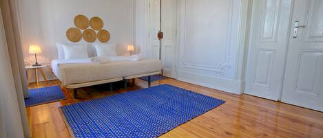 Un dormitorio con una cama, dos mesitas de noche, un tapete azul con diseño y una pared decorada con elementos circulares.