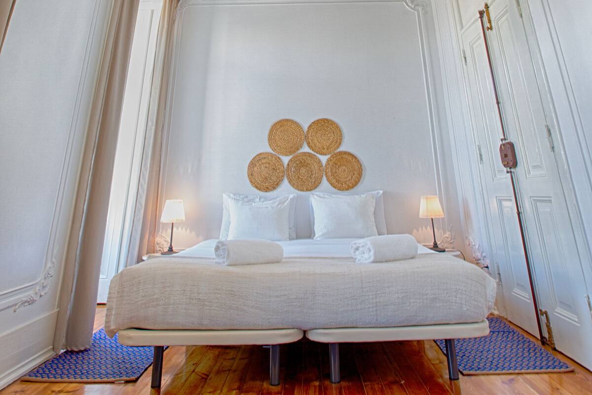 A bedroom with a large bed, ornate ceiling, and a hanging light fixture.