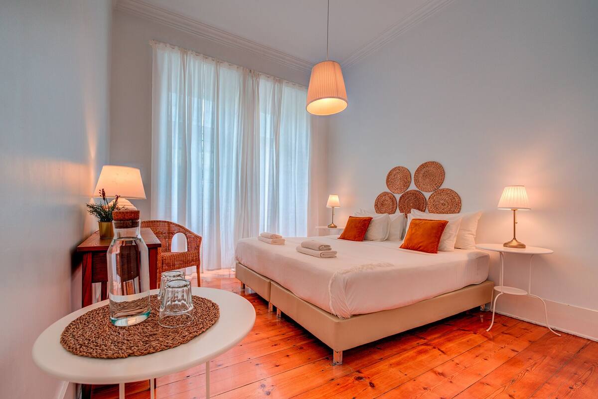 A bedroom with a bed, bedside tables, a round table, and a window with curtains.