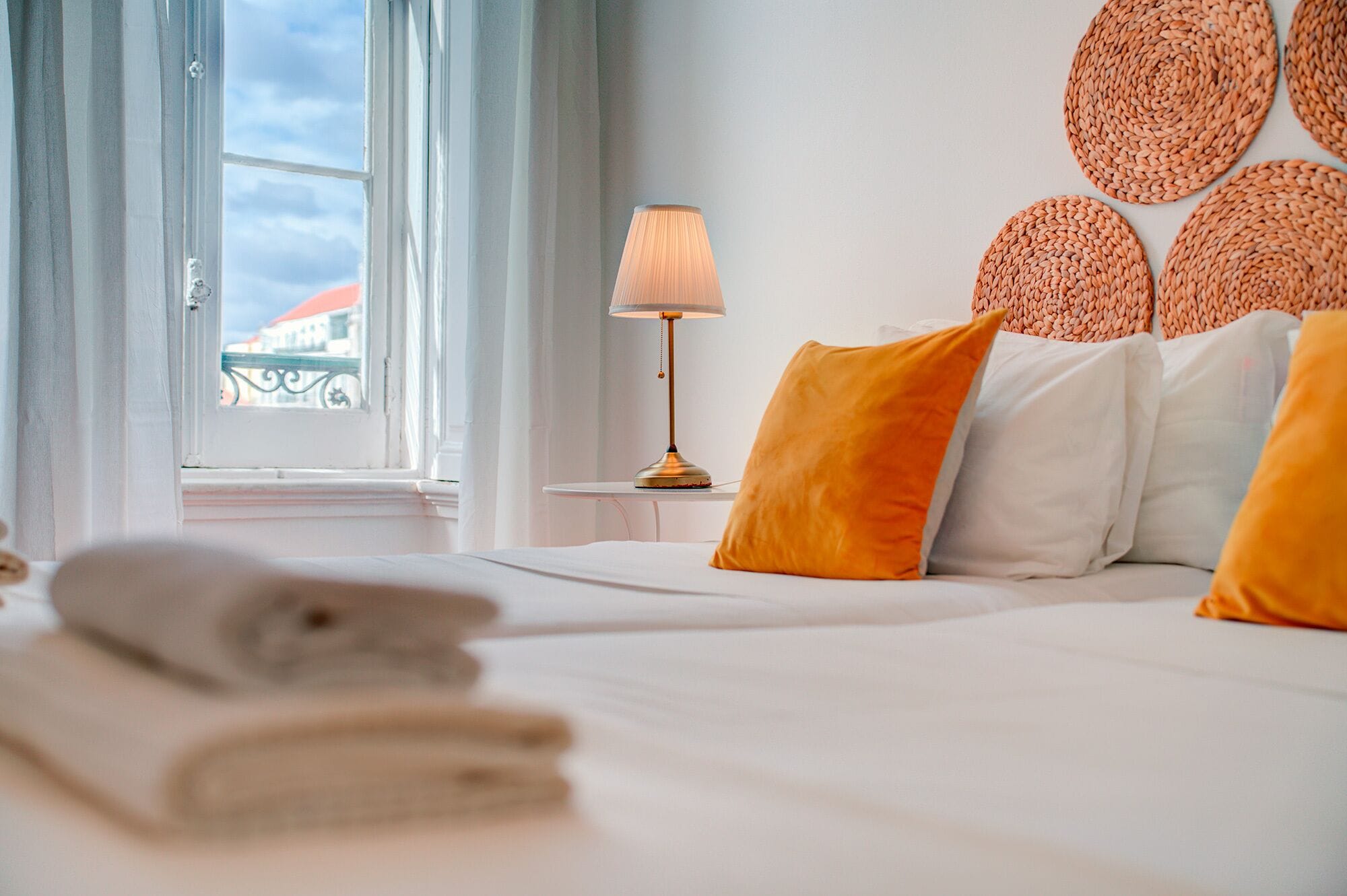 Una habitación de hotel con una cama, una lámpara y vistas al exterior.