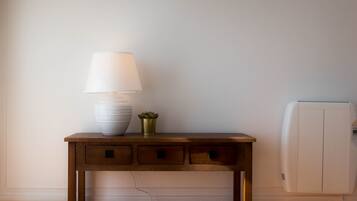 A wooden console table with a white lamp, a white vase, and a small plant.