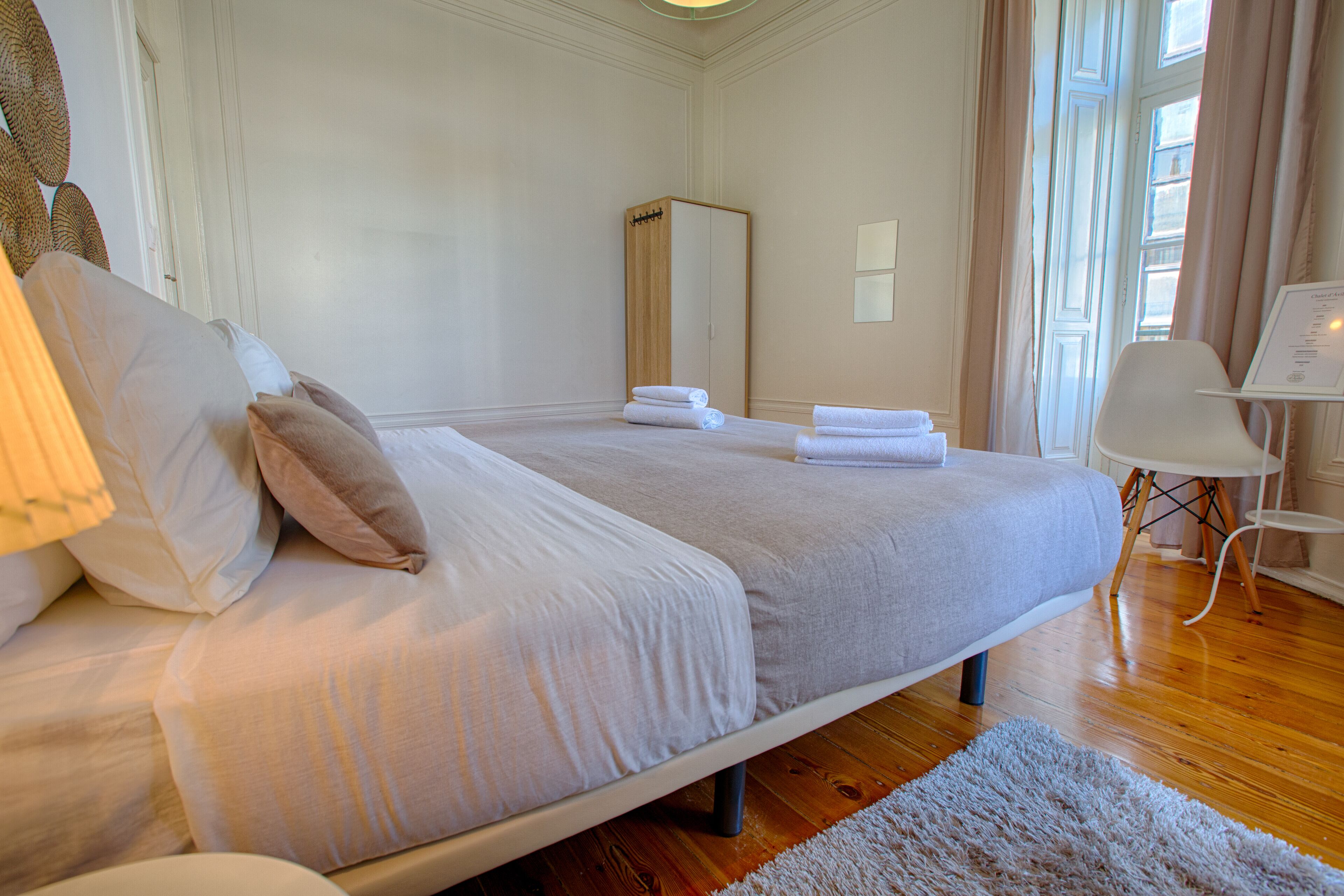 Une chambre bien rangée, avec un grand lit, une table de chevet, une chaise et un miroir.