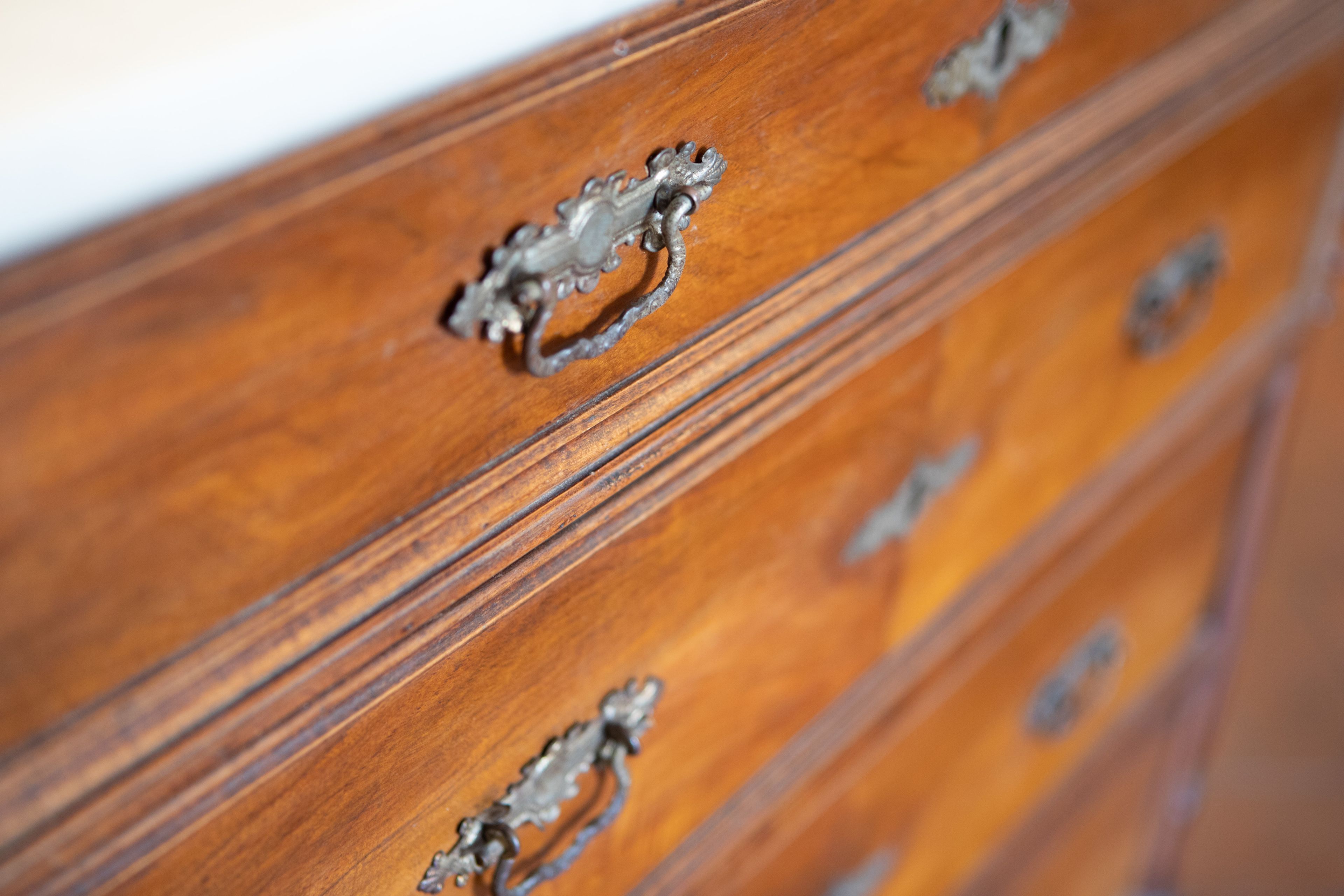 A wooden dresser with ornate metal handles.