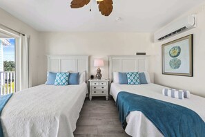 Ein Hotelzimmer mit zwei Betten, einem Nachttisch mit Lampe, einem gerahmten Bild an der Wand und einem Balkon mit Geländer.