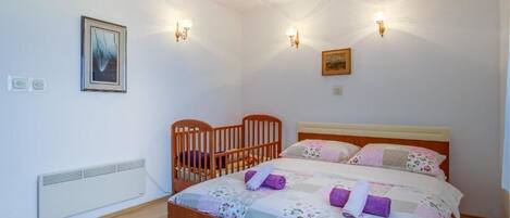 Une chambre à coucher avec un lit en bois, deux lampes fixées au mur, un radiateur et un tableau encadré accroché au mur.