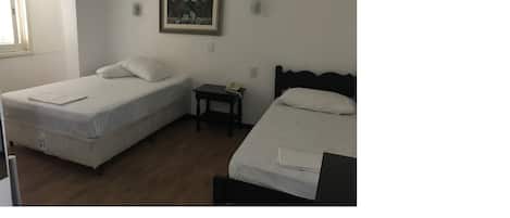 A room with two single beds, a small bedside table with a lamp, and a painting on the wall.