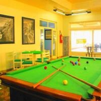 Una mesa de billar con bolas, un extintor y obras de arte enmarcadas en la pared.