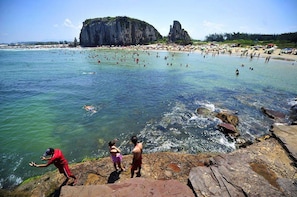 Escena de playa costera con costas rocosas y aguas cristalinas.