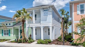 A two-story house with a balcony, surrounded by palm trees and a well-maintained garden. - Premium Cottage | Hot Tub + Margaritaville & Waterpark Access - 3025LA (Kissimmee)