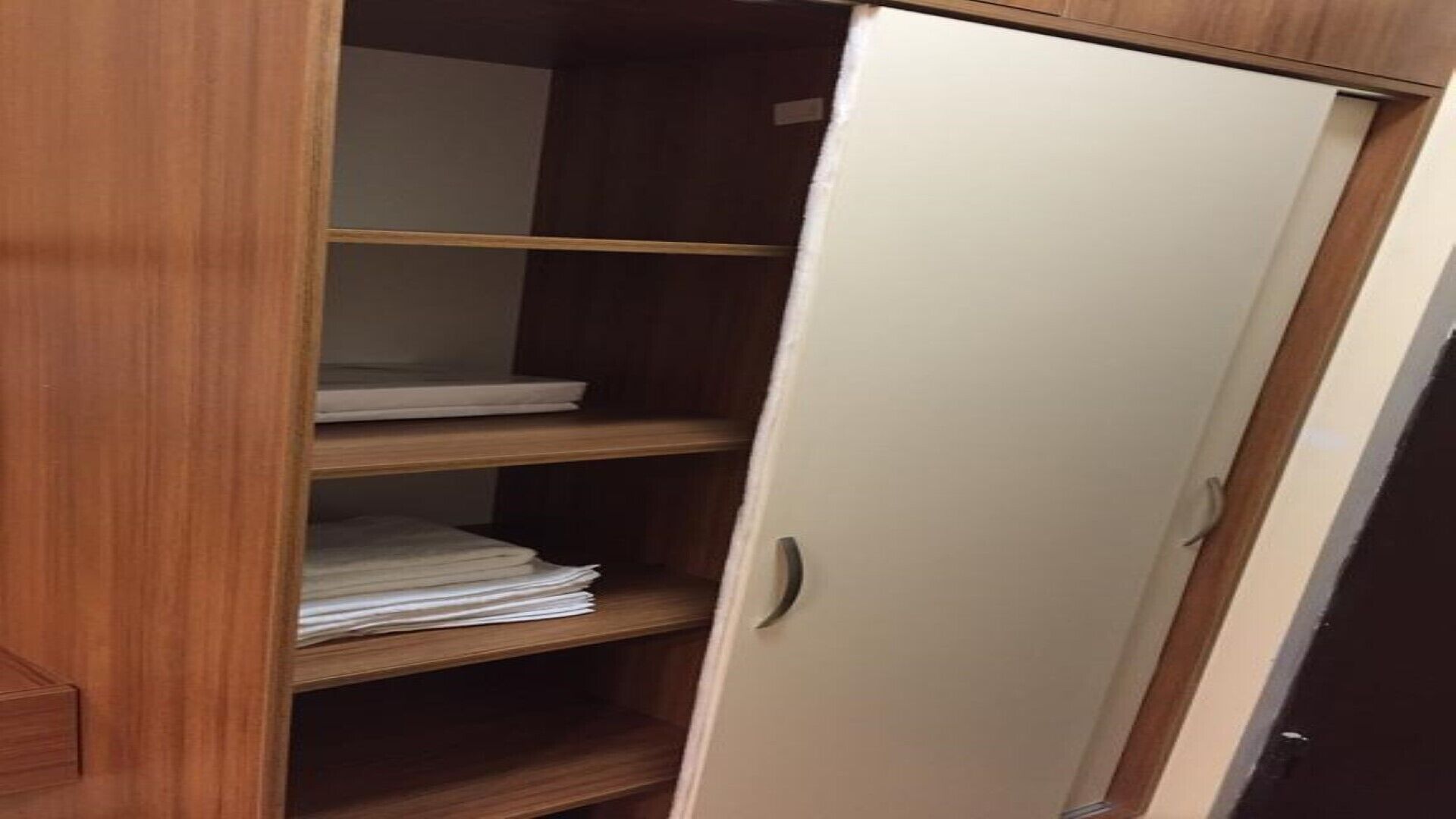 Un armario de madera con tres estantes y una puerta blanca.