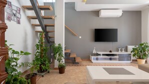A modern living room with a staircase, a flat-screen TV, and various potted plants. - Family villa Nicole in Štinjan (Štinjan)