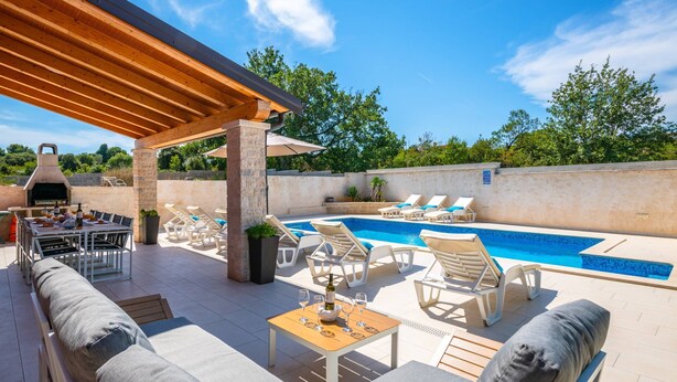 An outdoor patio with a pool, lounge chairs, a barbecue area, and a pergola. - Family villa Nicole in Štinjan (Štinjan)