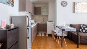 Een compacte keuken met moderne apparaten, een eetgedeelte met een tafel en stoelen, en een gezellige zithoek met een bank.