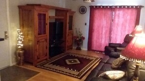 Uma sala de estar com um armário de madeira, um sofá, uma luminária e um ventilador de teto.