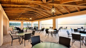 Une terrasse extérieure avec des tables et des chaises, des poutres en bois et des lanternes suspendues.