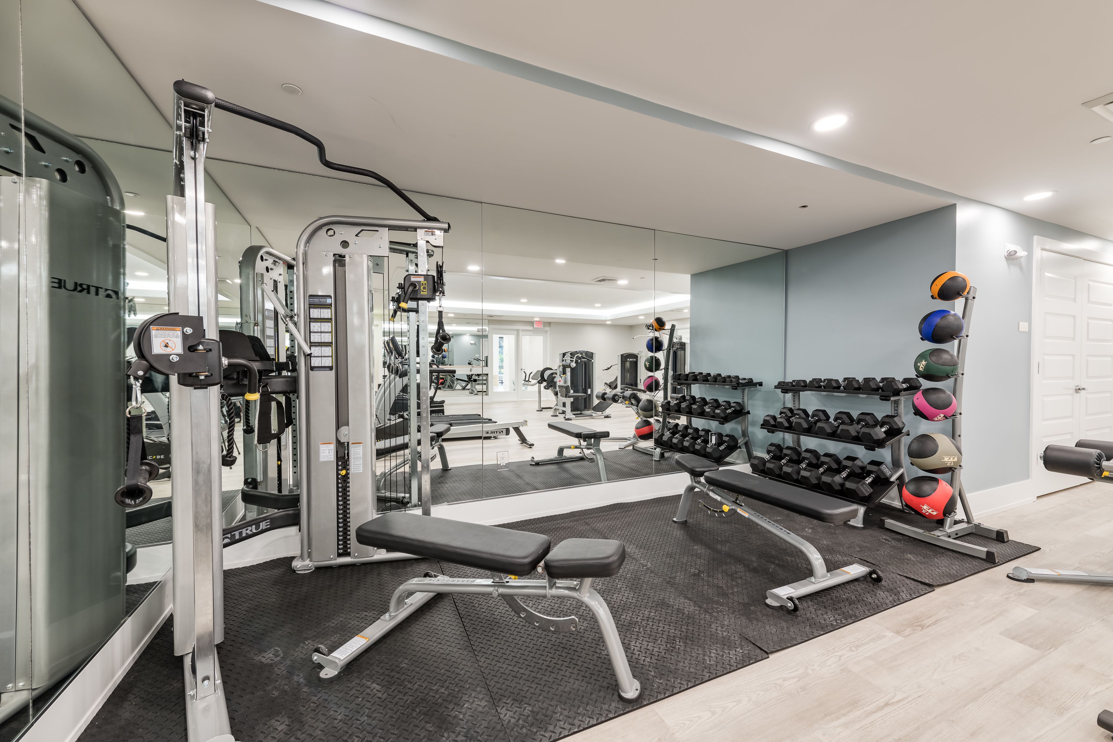 Een moderne sportschool met diverse trainingsapparaten, waaronder een squatsysteem, bank en gewichten.