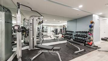 Ett modernt gym med olika typer av träningsutrustning, inklusive en knäböjsställning, en bänk och hantlar.