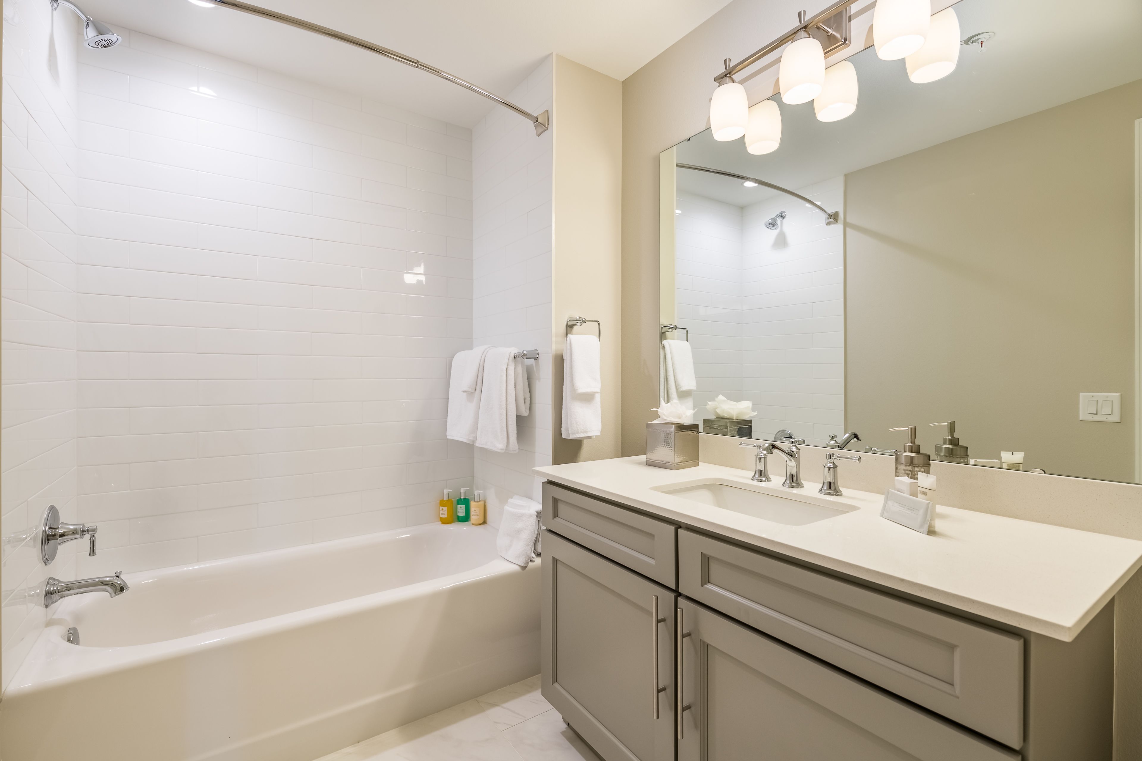 A modern bathroom with a bathtub, a vanity with a mirror, and a shower area.