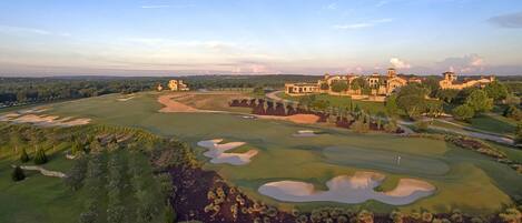 Un parcours de golf doté de bunkers, un club-house et un vaste domaine comprenant plusieurs bâtiments.