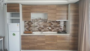 Een moderne keuken met houten kastjes, een betegelde spatwand en een inbouwkoelkast.