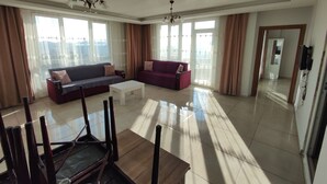 Een ruime woonkamer met twee banken, een salontafel en een eethoek met stoelen.